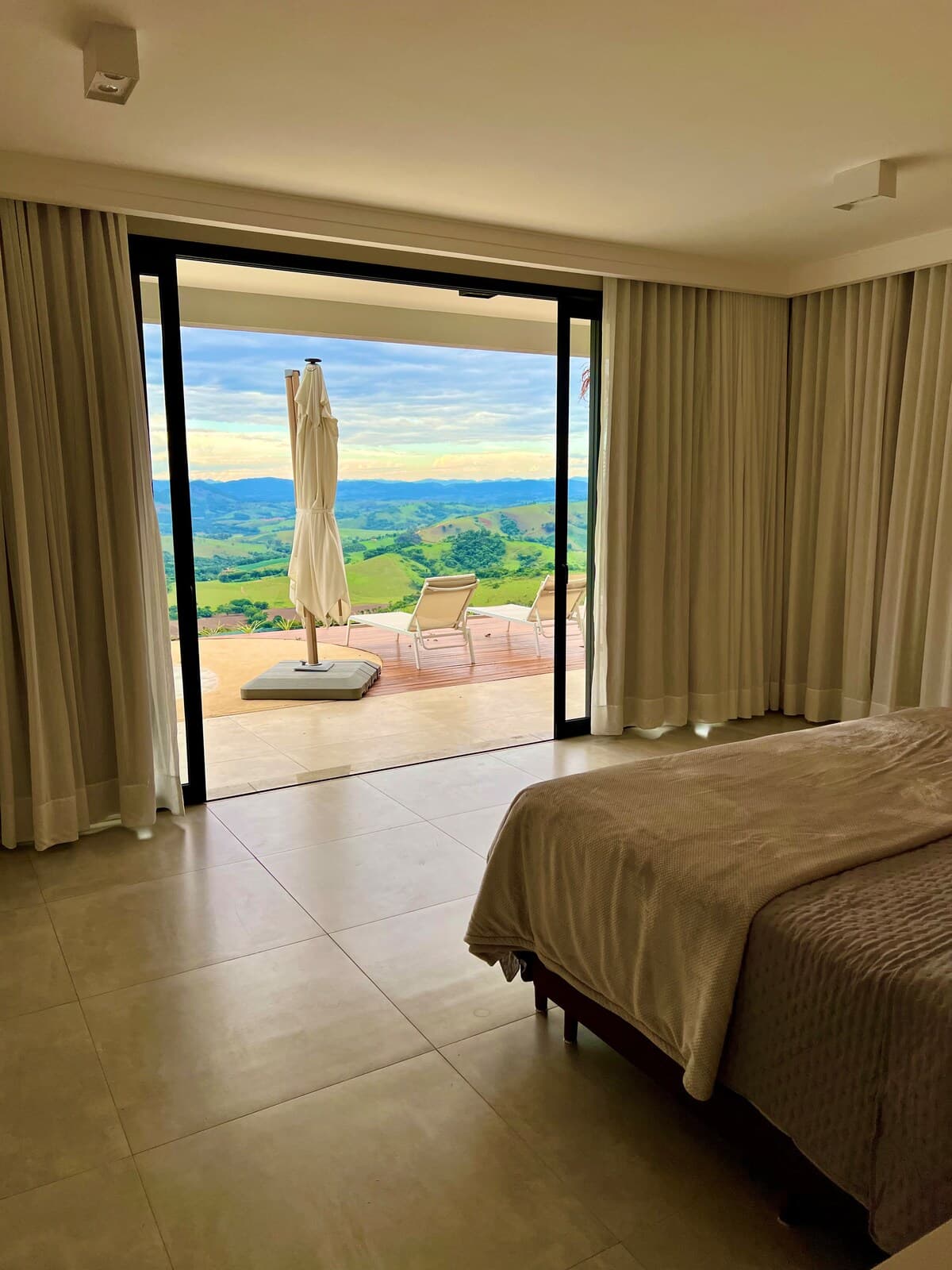 Quarto com cama voltada para varanda e vista da montanha